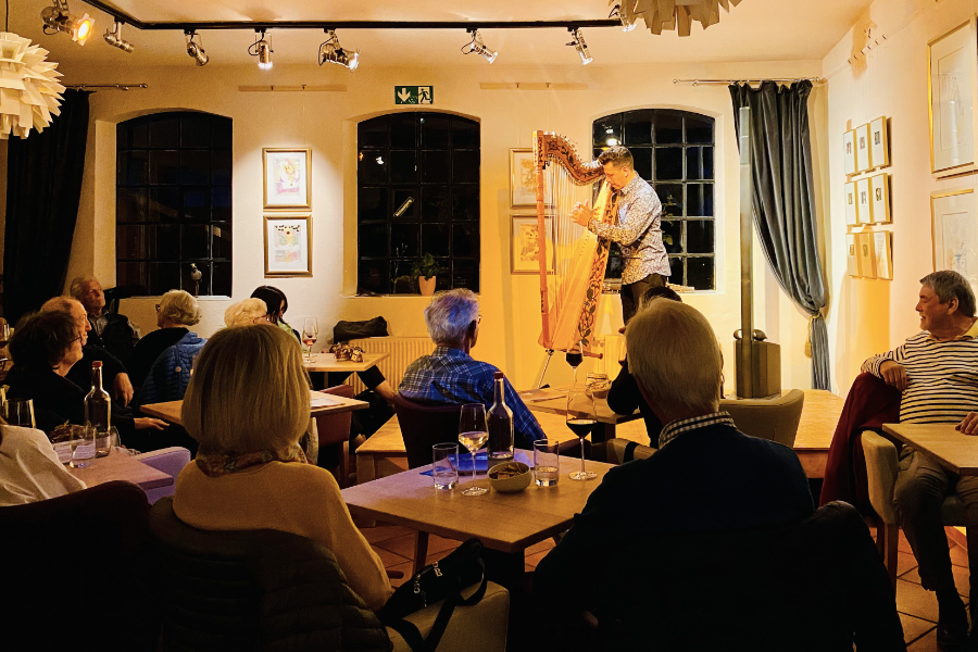 saxyarpa in der Alten Druckerei auf Föhr. Alberto spielt Harfe auf der Bühne der Weinstube.