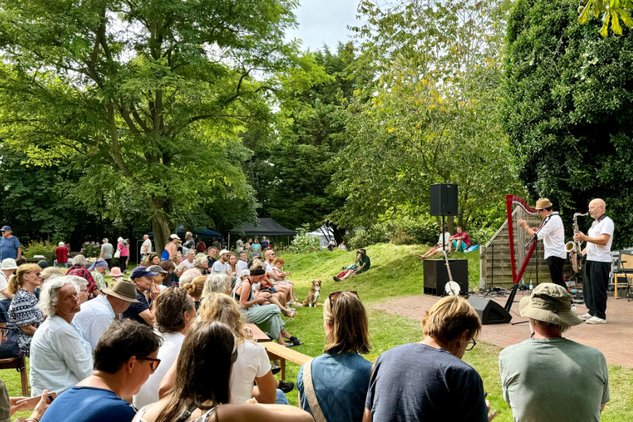 saxyarpa im Kurpark Nebel auf Amrum zwei Musiker mit Harfe und Saxophon vor Publikum im Kurpark auf der Außenbühne.